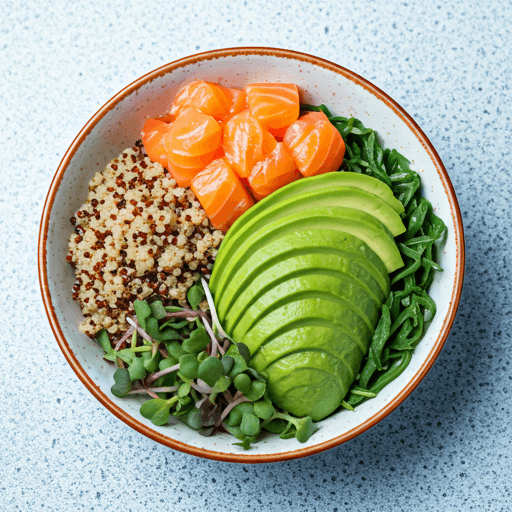 Top down view of a vibrant gourmet fitness bowl with sliced avocado, quinoa, salmon, and microgreens on a light stone texture